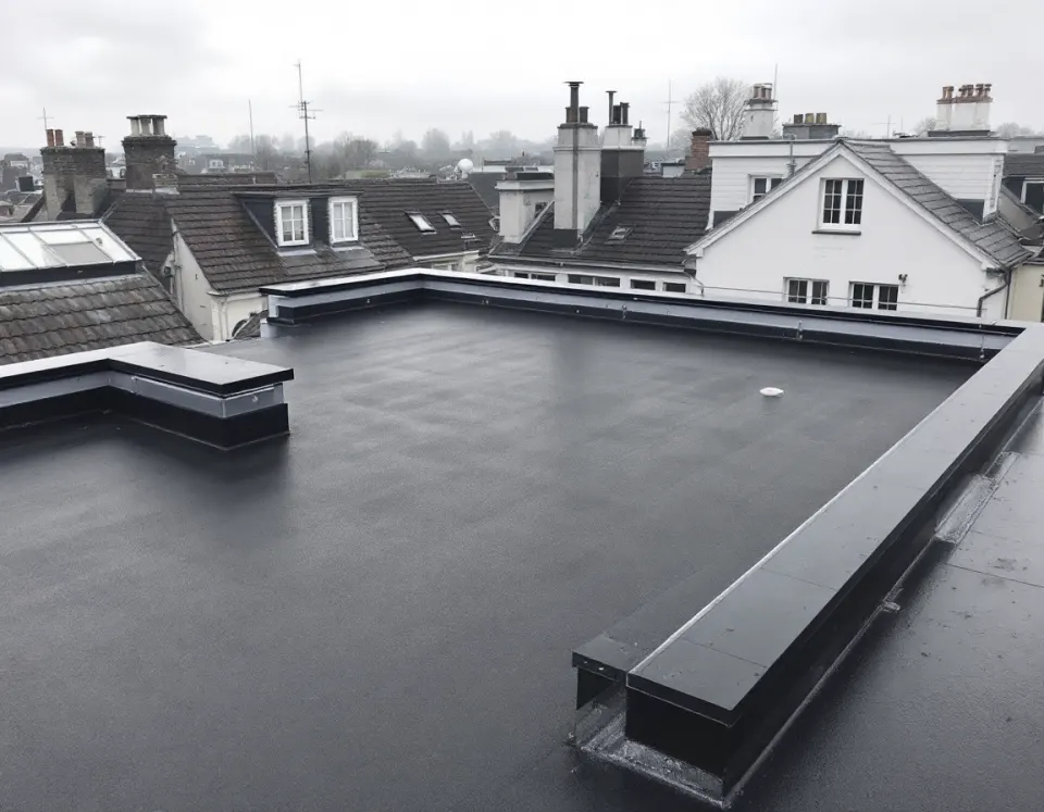 Toiture plate terminée : membrane EPDM sombre, soudures nettes, couvre-mur en zinc et avaloir unique